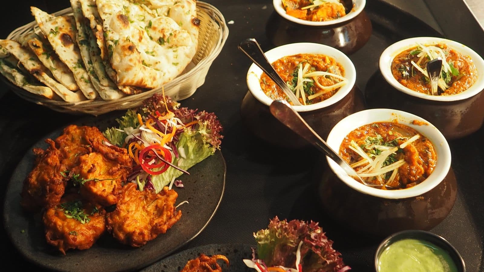 Stock photograph of a spread of curries, bread, and sharing plates