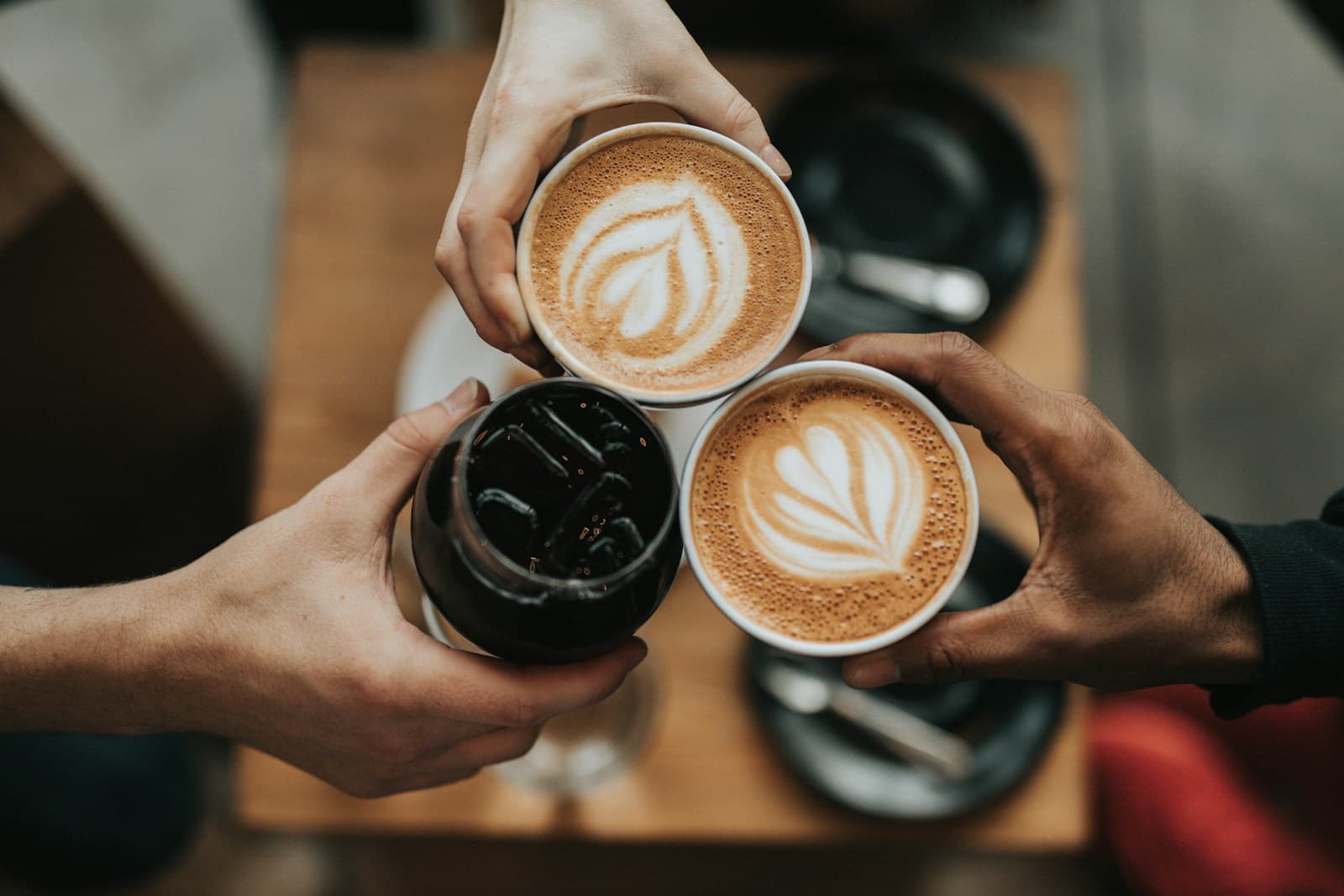 Stock photograph of friends holding cups of coffee together